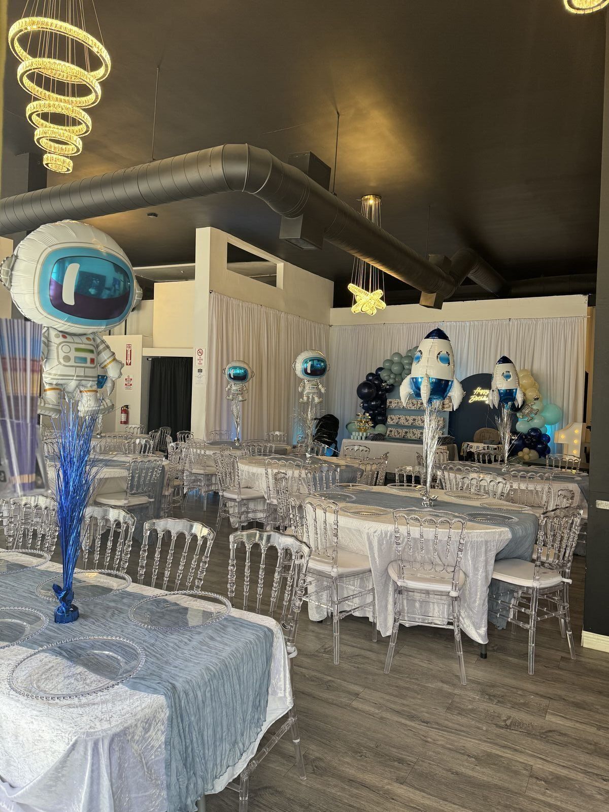 Blue-themed baby shower with tables and ghost chairs