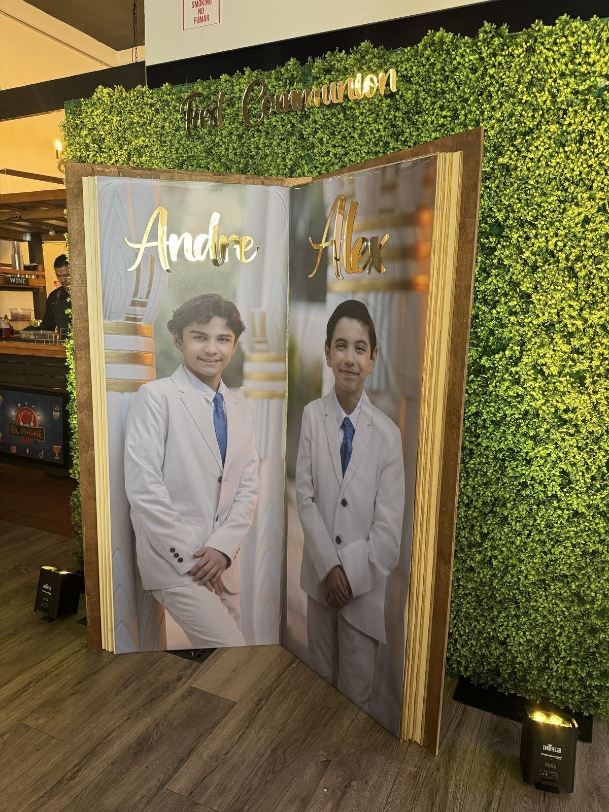 Baptism celebration display with green hedge backdrop
