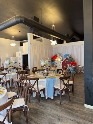 Farm and barnyard themed baby shower at The Prestige Venue with red barn backdrop, round tables, and cross-back chairs