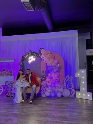 First birthday butterfly theme celebration at The Prestige Venue with purple lighting, balloon tower, and family photo