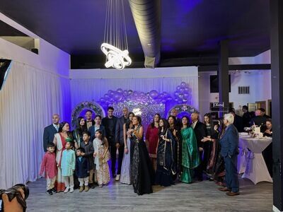 Large group celebration at The Prestige Venue with purple and blue lighting and balloon backdrop
