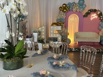 Quinceañera setup at The Prestige Venue with 15 marquee, pink and gold balloon arch, and ghost chairs