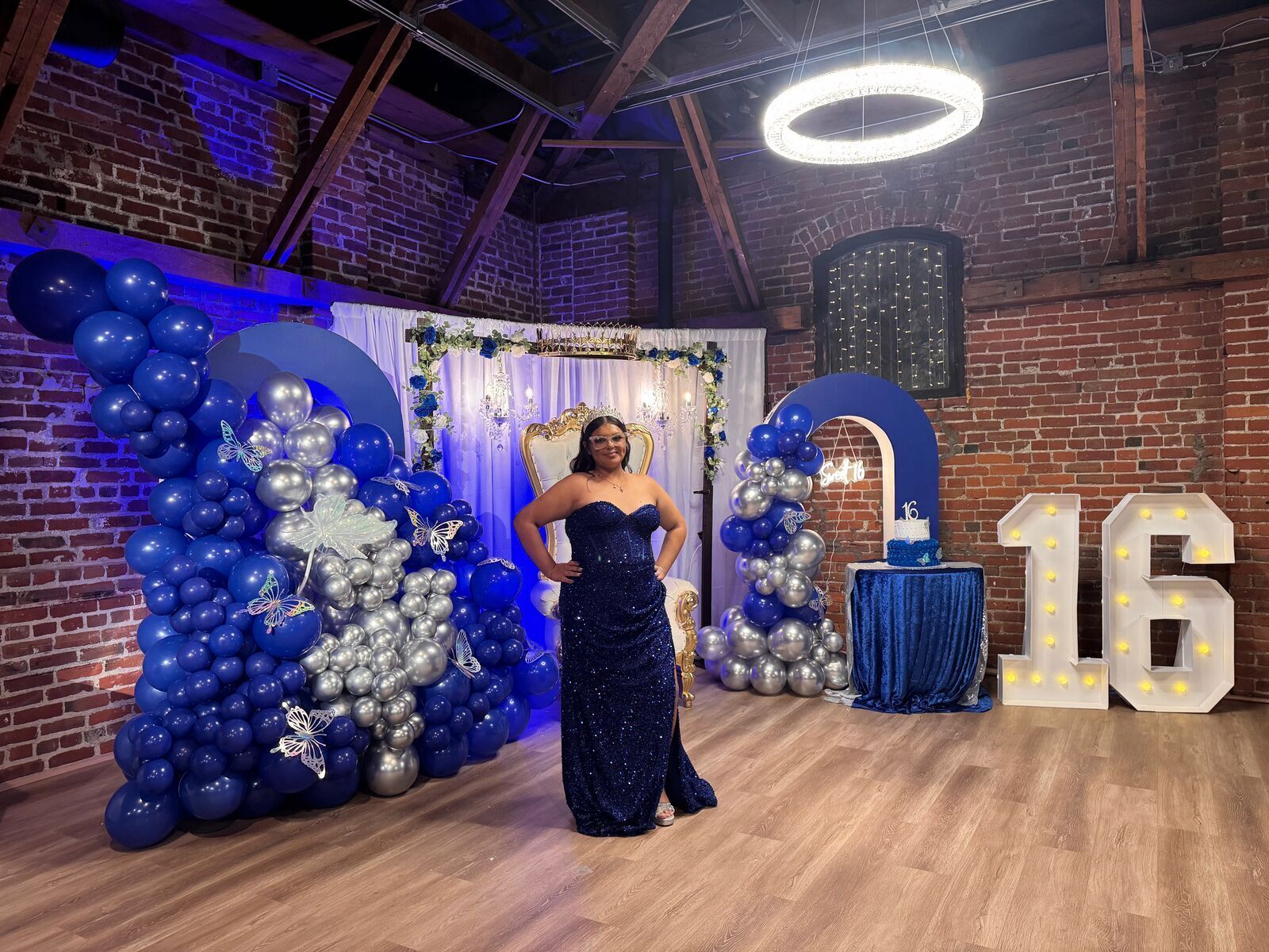 Sweet 16 celebration at The Prestige Hall with guest posing in front of blue and silver balloon display