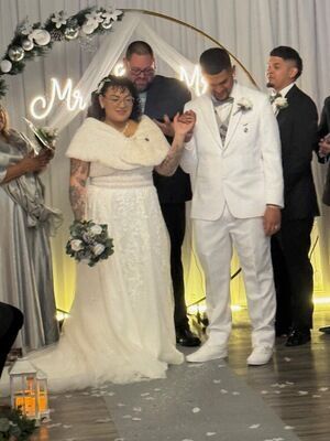 Bride and groom at altar during wedding ceremony at The Prestige Venue with Mr and Mrs neon sign